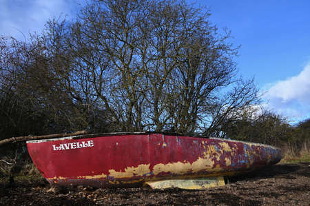 A view of old boats on a seaweed covered beach on the coast of Limekilns in Fife, Scotland.の写真素材