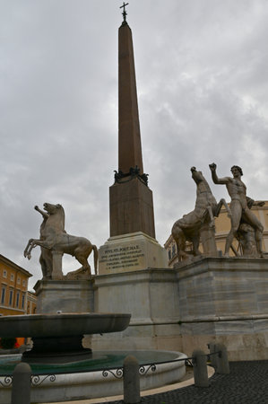 A view of an ornate stone obelisk in a piazza in the city of Rome in Italy.の写真素材