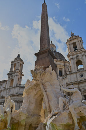 A view of an ornate stone obelisk in a piazza in the city of Rome in Italy.の写真素材