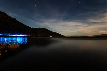 Bassenthwaite lake in the lake district with the lights of a police car on the a66 reflecting on the lakeの写真素材
