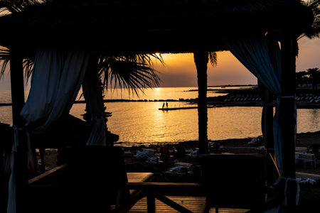 A view of a stunning orange sky lighting up the cost of paphos island of Cyprusの写真素材