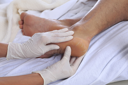Healthcare environment with caregiver checking patients footの写真素材