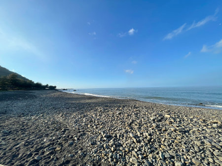 Stones on the beach and blue sky with white clouds in the morningの写真素材