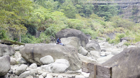 Unidentified people sitting on the rocks at the river.