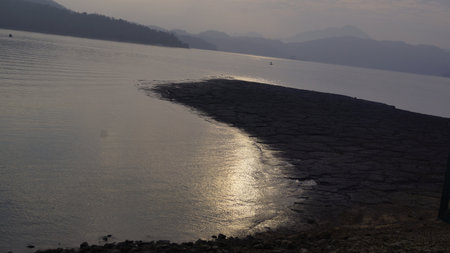 Sunset on the lake with a boat and mountains in the backgroundの写真素材