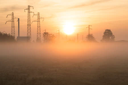 Suburban sunrise over the town, with pylons on backgroundの写真素材