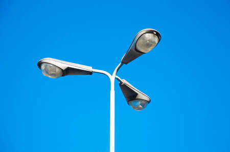 Detail of a street lamp post, three lights in a blue skyの写真素材
