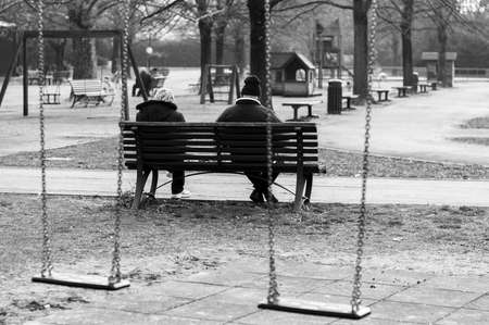 Senior couple sitting on a bench in a playgroundの写真素材