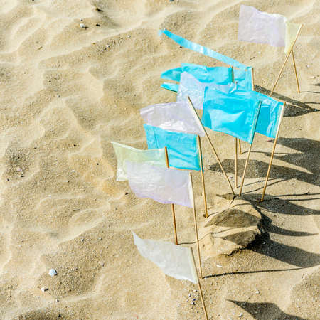 Series of small blue and white flags on the beach