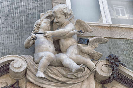 Stone statue baby angel plays with a young childの写真素材