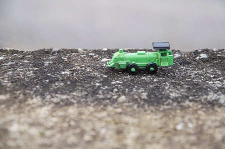 Green steel toy train in an asphalt background, conceptual photoの写真素材