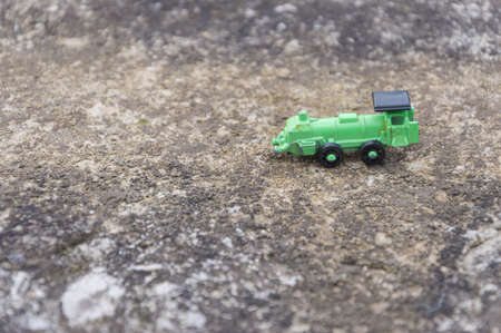 Green steel toy train in an asphalt background, conceptual photoの写真素材