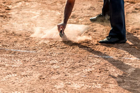 Referee cleans home plate in a baseball (softball) dusty field, with copyspaceの写真素材