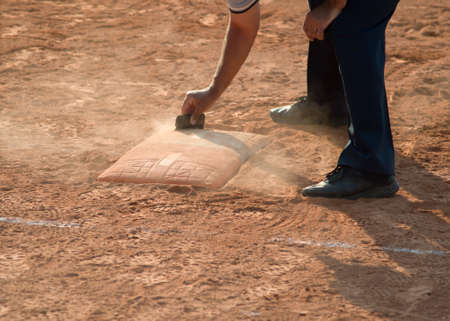 Referee cleans home plate in a baseball (softball) dusty field, with copyspaceの写真素材