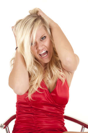 A woman angry and mad in a red dress holding on to her hair.の写真素材