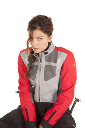 A woman in her biker clothes sitting on a stool with a serious expression on her face.の写真素材