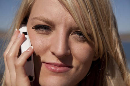 a close up of a woman on the phone talking with  a small smile on her lips.の写真素材