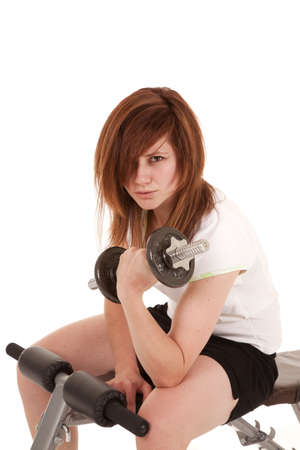A woman sitting on a weight bench working out her arms.の写真素材
