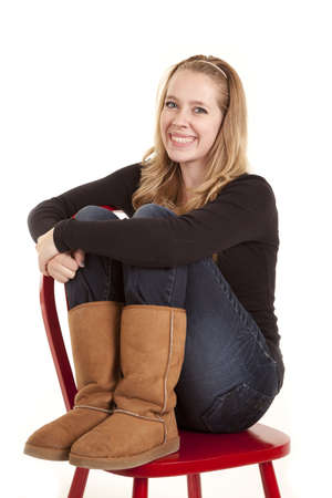 A girl sitting on a red chair with a smile on her face.の写真素材