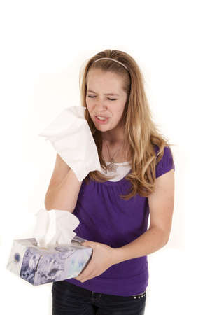 A teenage girl holding a box of tissues getting ready to sneeze.の写真素材
