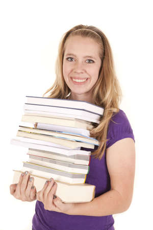 A teenager with a stack of books with a smile on her face.の写真素材