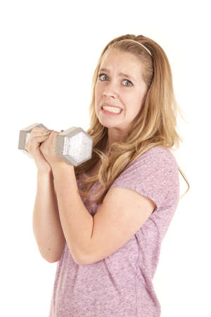 A girl holding a big weight with two hands showing a lot of effort.の写真素材
