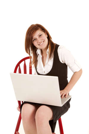 A woman sitting and working on her computer with a smile on her face.の写真素材