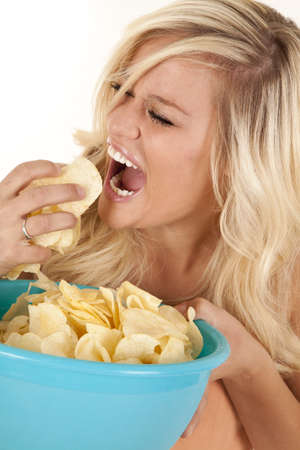 a woman with a big bowl full of chips getting ready to take a huge mouth full of chips の写真素材