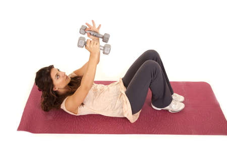 A woman laying on her back lifting weights and working out.の写真素材