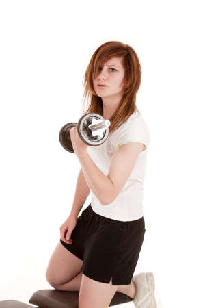 A woman with her knee on a workout bench working out her arm.の写真素材