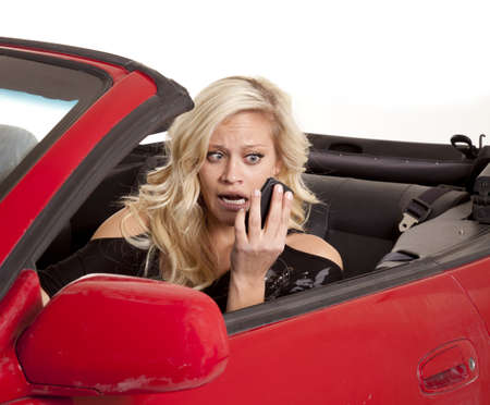 A woman looking at her cell phone with a  funny expression on her face while driving her car.の写真素材