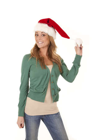 A woman standing and holding on to the ball on her Santa hat with a big smile on her face.の写真素材