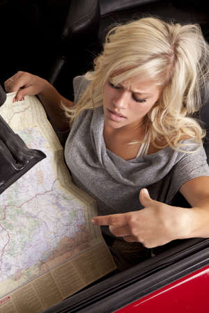 A woman is sitting in a car looking at a map. She looks confused and unhappy.の写真素材