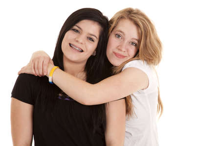 A teen girl hanging on to her bestfriend with a smile on their face.の写真素材