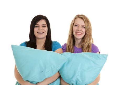 Two teen girls holding on to their pillows smiling.の写真素材