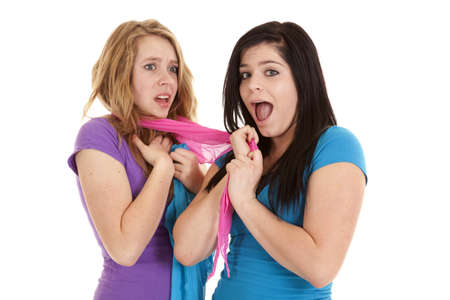 A teen girl showing her happy expression while she has wrapped a sarong around her friends neck.の写真素材