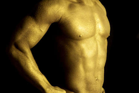 A close up of a man's chest painted gold.の写真素材