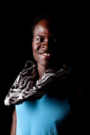 A man with a blue tank on with his track shoes wrapped around his neck.