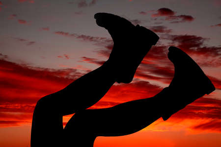 A woman wearing her cowboy boots putting them up in the beautiful sunset.の写真素材