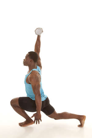 A man doing a lunge while he lifts a weight with one arm.の写真素材