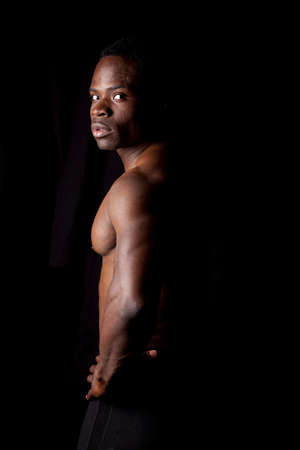 A man standing sideways showing off his muscles with a serious expression on his face.の写真素材