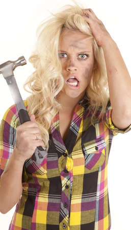A woman is holding a hammer in her hand and looks very frustrated.の写真素材