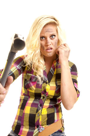 A woman is holding out a hammer and looks mad.の写真素材