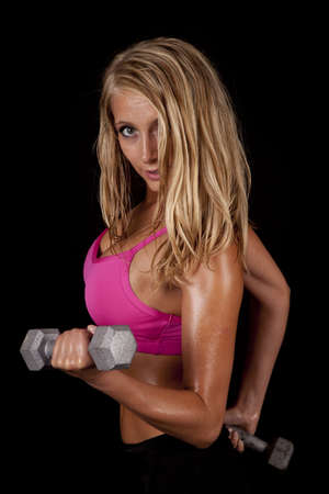 A woman with sweat dripping off of her body working out with weights.の写真素材