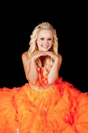 a beautiful teen in her bright orange dress playing princess with her crown.の写真素材