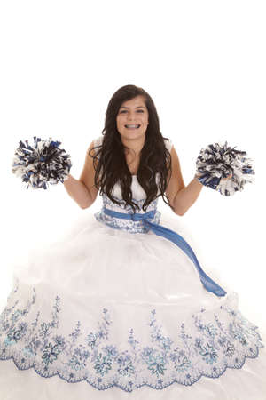 a teen girl in her white formal dress with a smile on her face holding up her pom pomsの写真素材