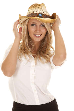 A close up of a woman in her hat with a smile on her face holding on to her hat.の写真素材