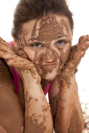 A close up of a woman's face with mud all over her cheeks and hands.の写真素材