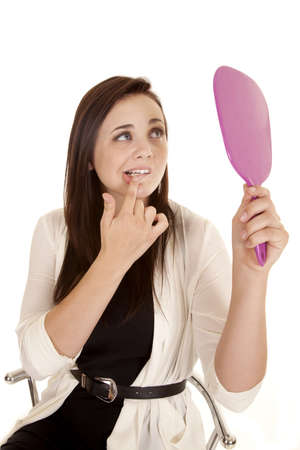 A woman fiddling with her lip while looking in the mirror.の写真素材