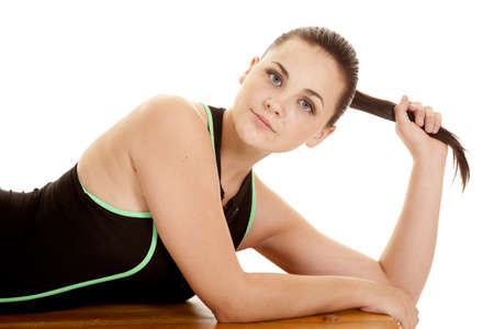 A woman laying on a bencn in her black and green workout top with a serious expression on her face holding on to her pony tailの写真素材